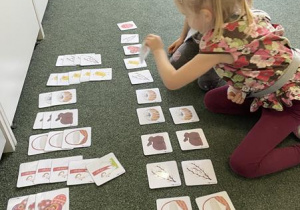 dziewczynki na dywanie przyporządkowują obrazki z wielkanocnymi symbolami